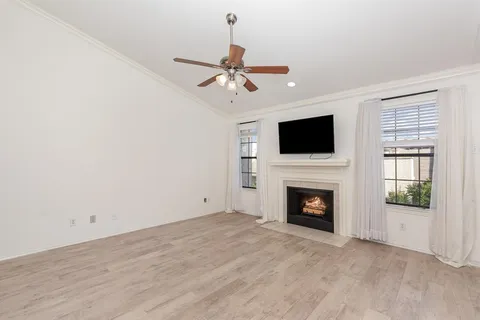 a view of a livingroom with a fireplace a ceiling fan and wooden floor