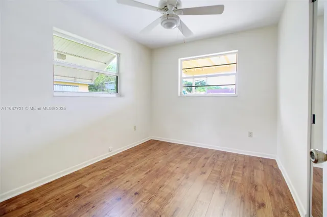 an empty room with wooden floor fan and windows