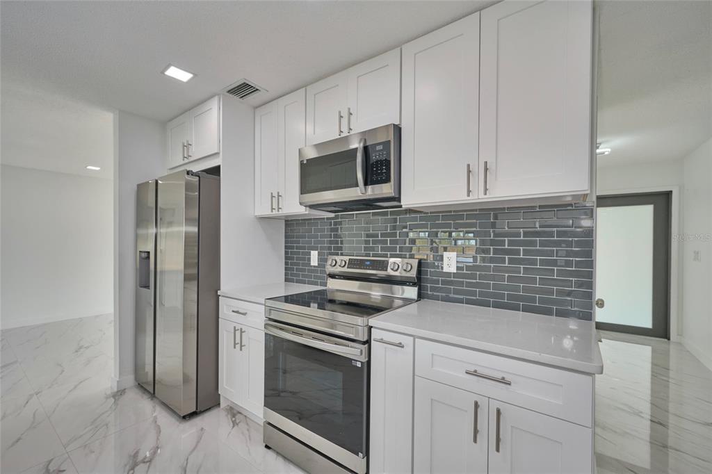 2310 Laguna Drive Indian Lake Estates, FL 33843 - Photo 6 of 27 a kitchen with stainless steel appliances white cabinets and stove