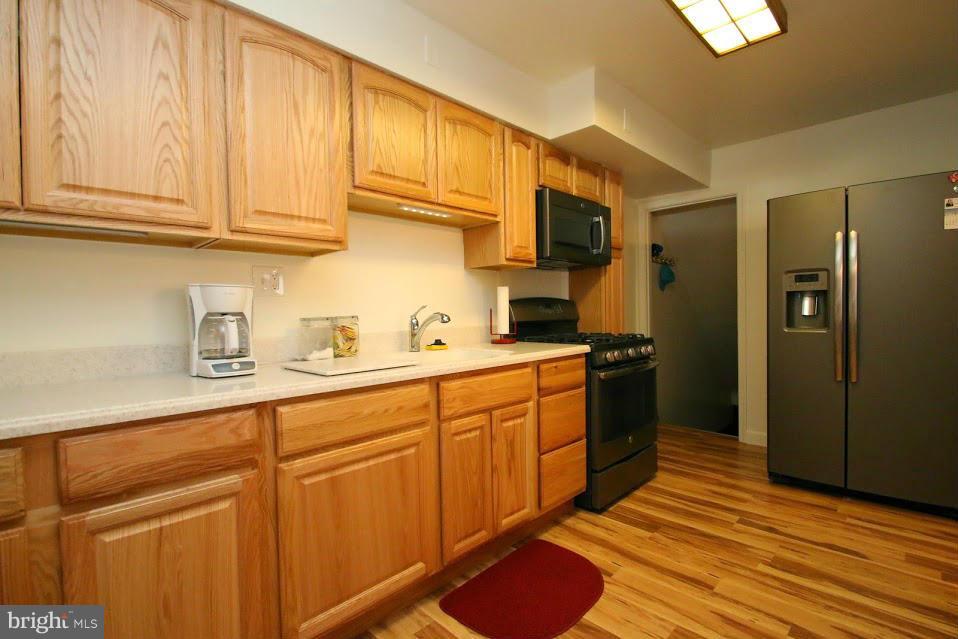 1711 Stokesley Road Baltimore, MD 21222 - Photo 12 of 30 a kitchen with stainless steel appliances granite countertop a sink cabinets and wooden floor