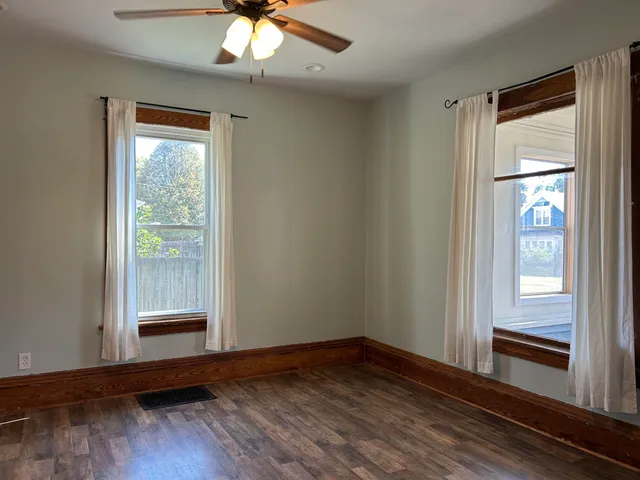a view of an empty room with wooden floor and a window