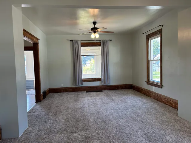 an empty room with windows and chandelier fan