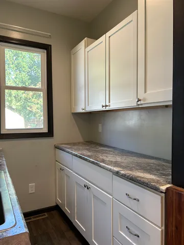 a kitchen with granite countertop white cabinets and a window