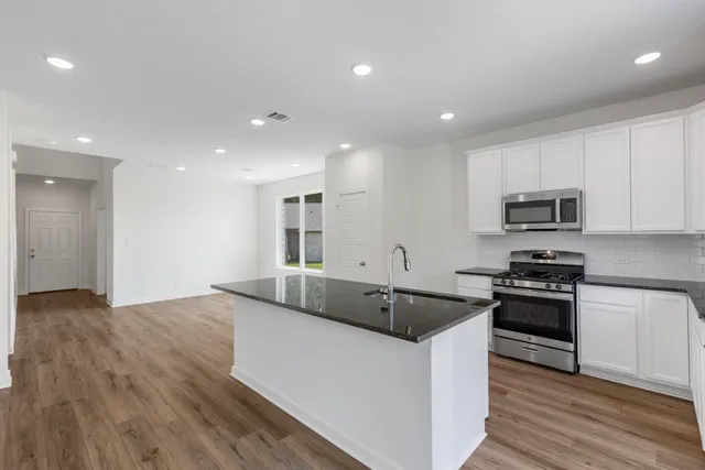 a kitchen with stainless steel appliances granite countertop a stove a sink and a wooden floors