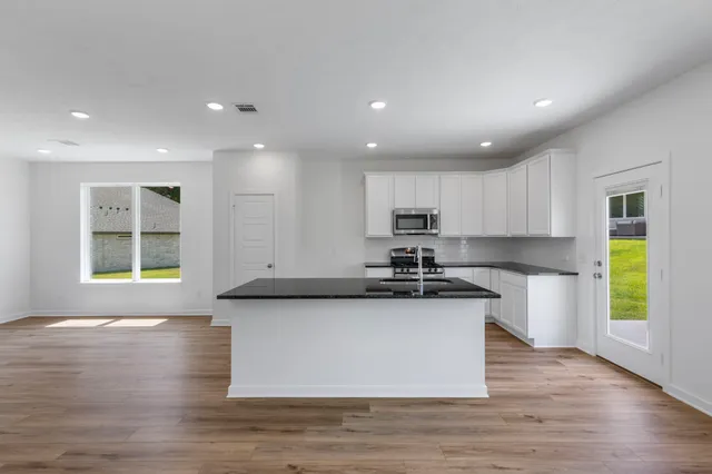a kitchen with kitchen island granite countertop a sink and wooden floors