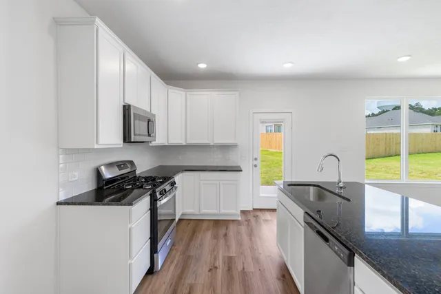 a kitchen with granite countertop a stove and wooden floor