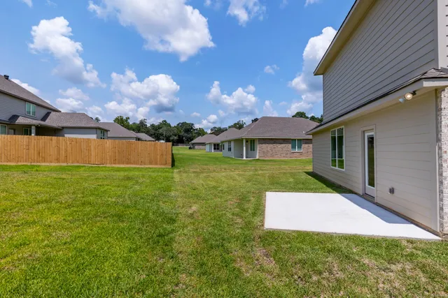 a view of a house with a yard and a large tree