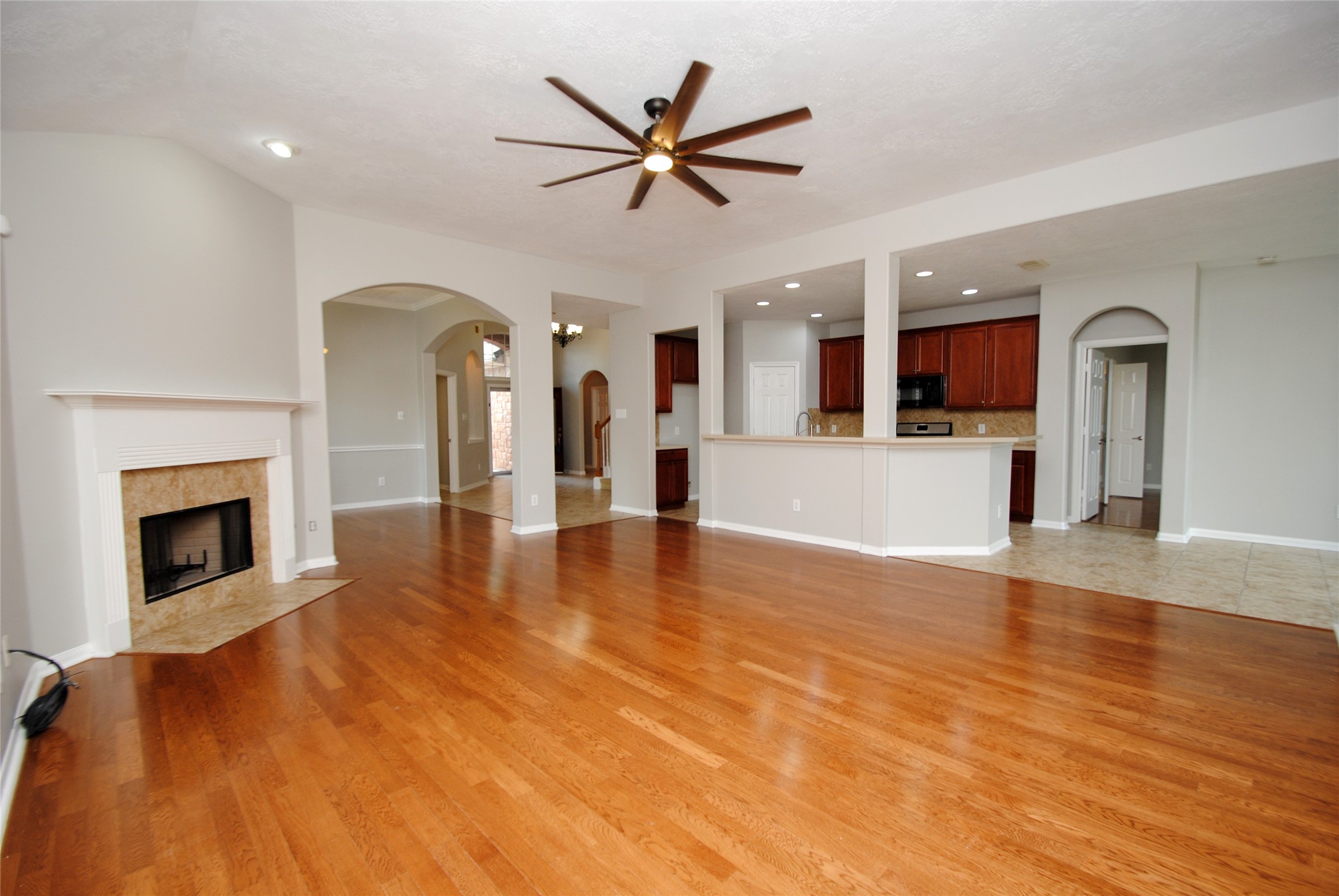13409 Garden Spring Court Rosharon, TX 77583 - Photo 16 of 38 a view of a livingroom with a fireplace a ceiling fan and a kitchen view