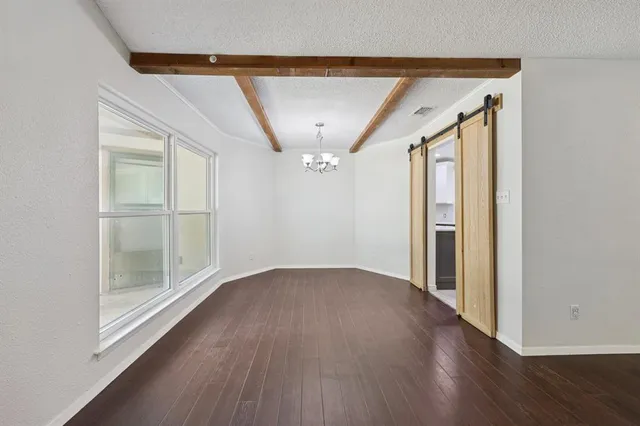 an empty room with wooden floor and a hallway