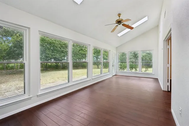 a view of empty room with wooden floor and fan
