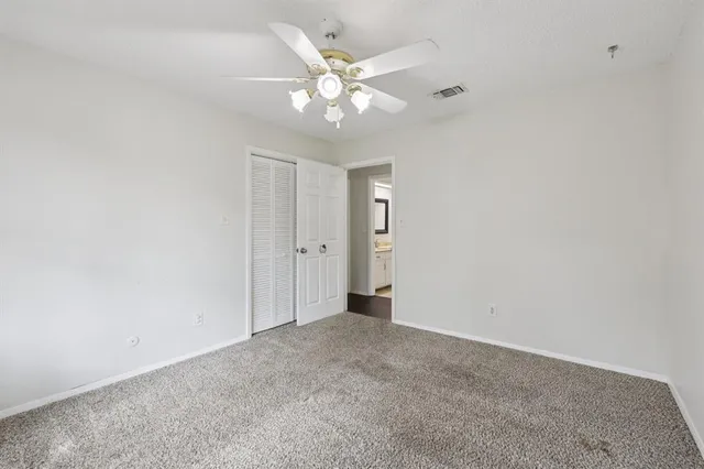 an empty room with a chandelier fan and windows