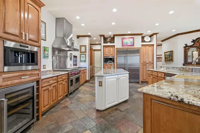 a large kitchen with stainless steel appliances kitchen island granite countertop a large counter top and wooden cabinets