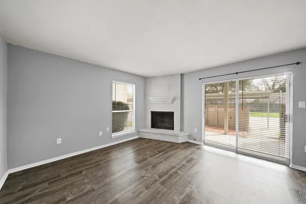 an empty room with wooden floor fireplace and windows