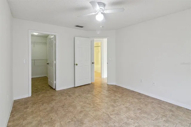 an empty room with closet and a ceiling fan