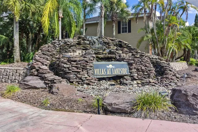 a view of a stone house with a yard and large tree