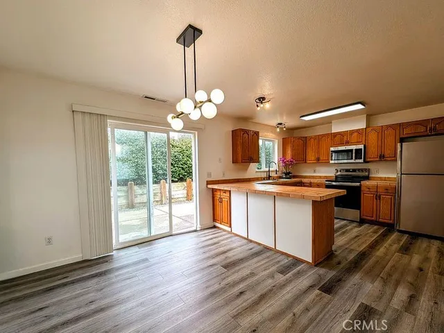 a kitchen with stainless steel appliances kitchen island granite countertop a refrigerator a oven a stove and a wooden floors