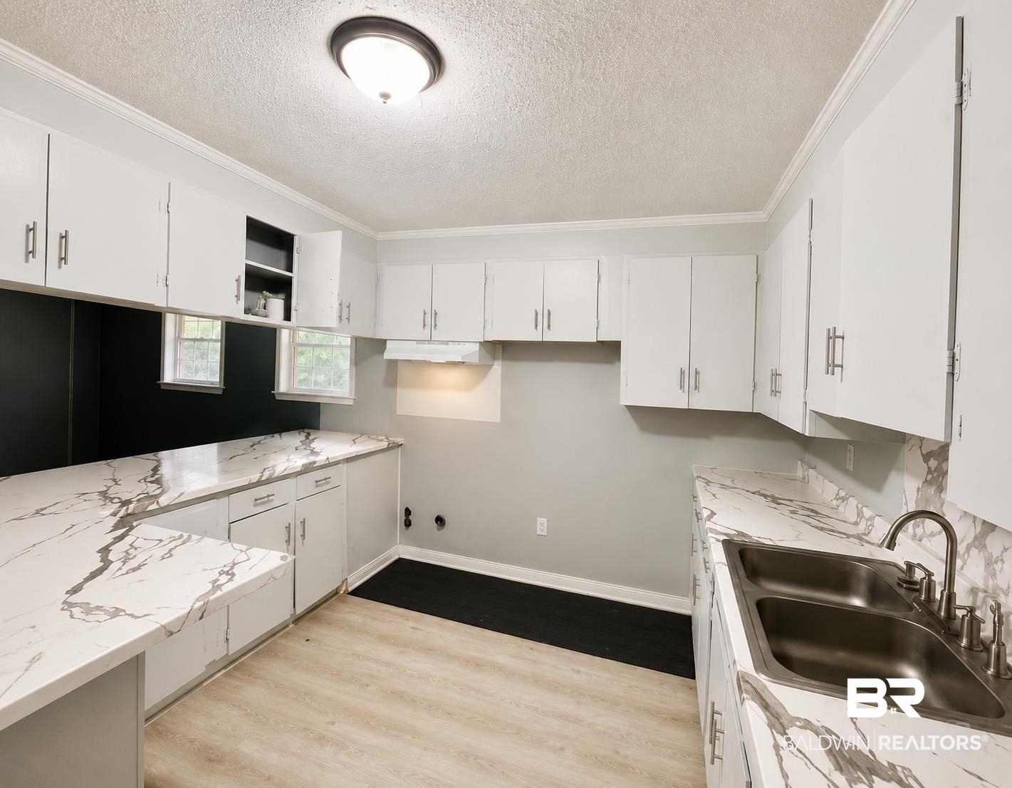 226 Elizabeth Street Evergreen, AL 36401 - Photo 12 of 35 Kitchen featuring extensive counter space with a marble-look finish, white cabinetry, a double basin stainless steel sink with a high-arc faucet, and wood-finish flooring