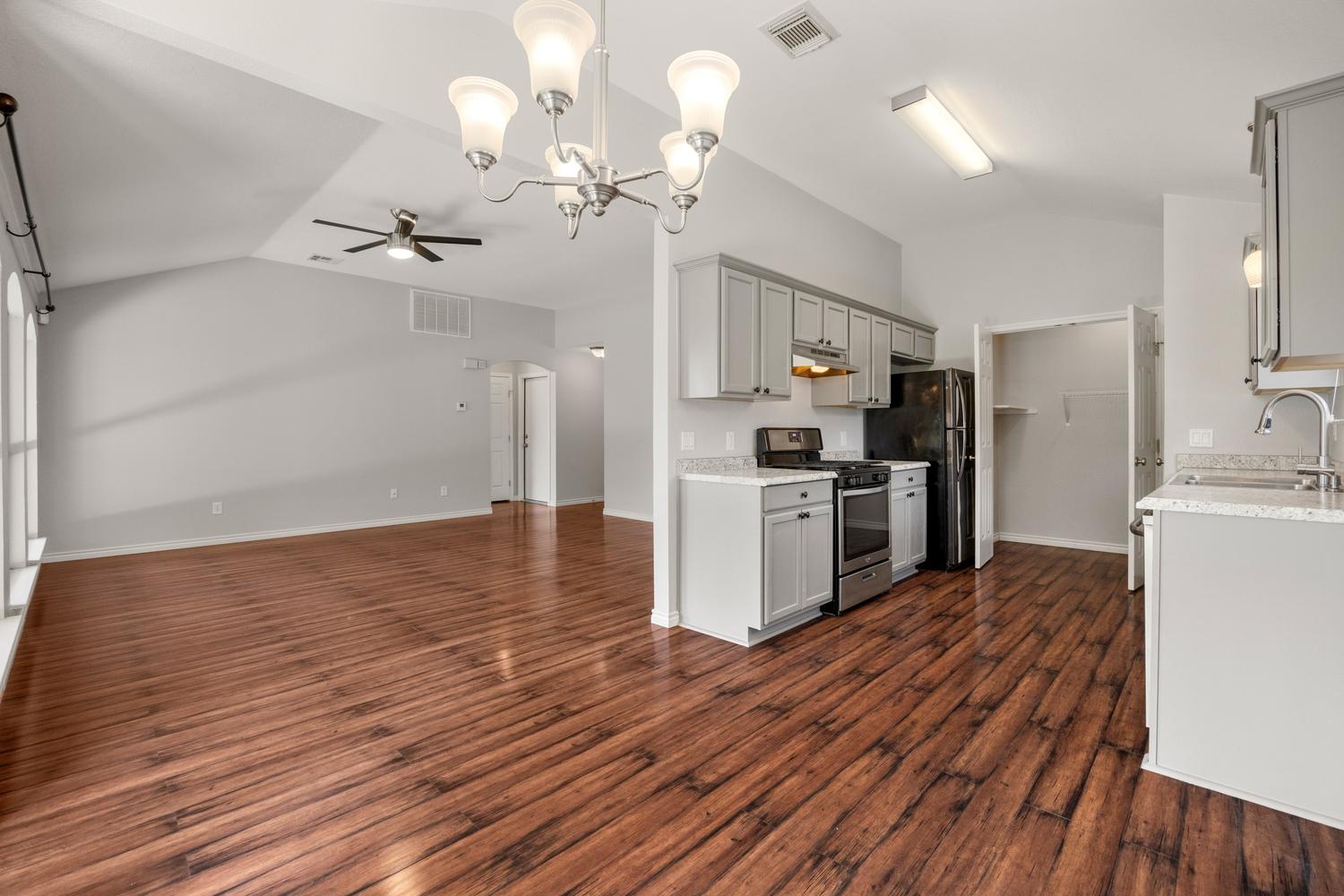 521 Britni Loop Kyle, TX 78640 - Photo 8 of 23 a kitchen with stainless steel appliances granite countertop a refrigerator a sink dishwasher a stove and white countertops with wooden floor