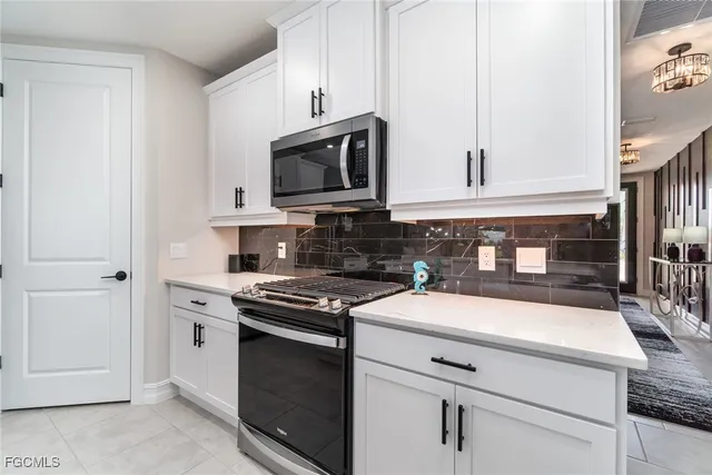 a kitchen with white cabinets and black appliances
