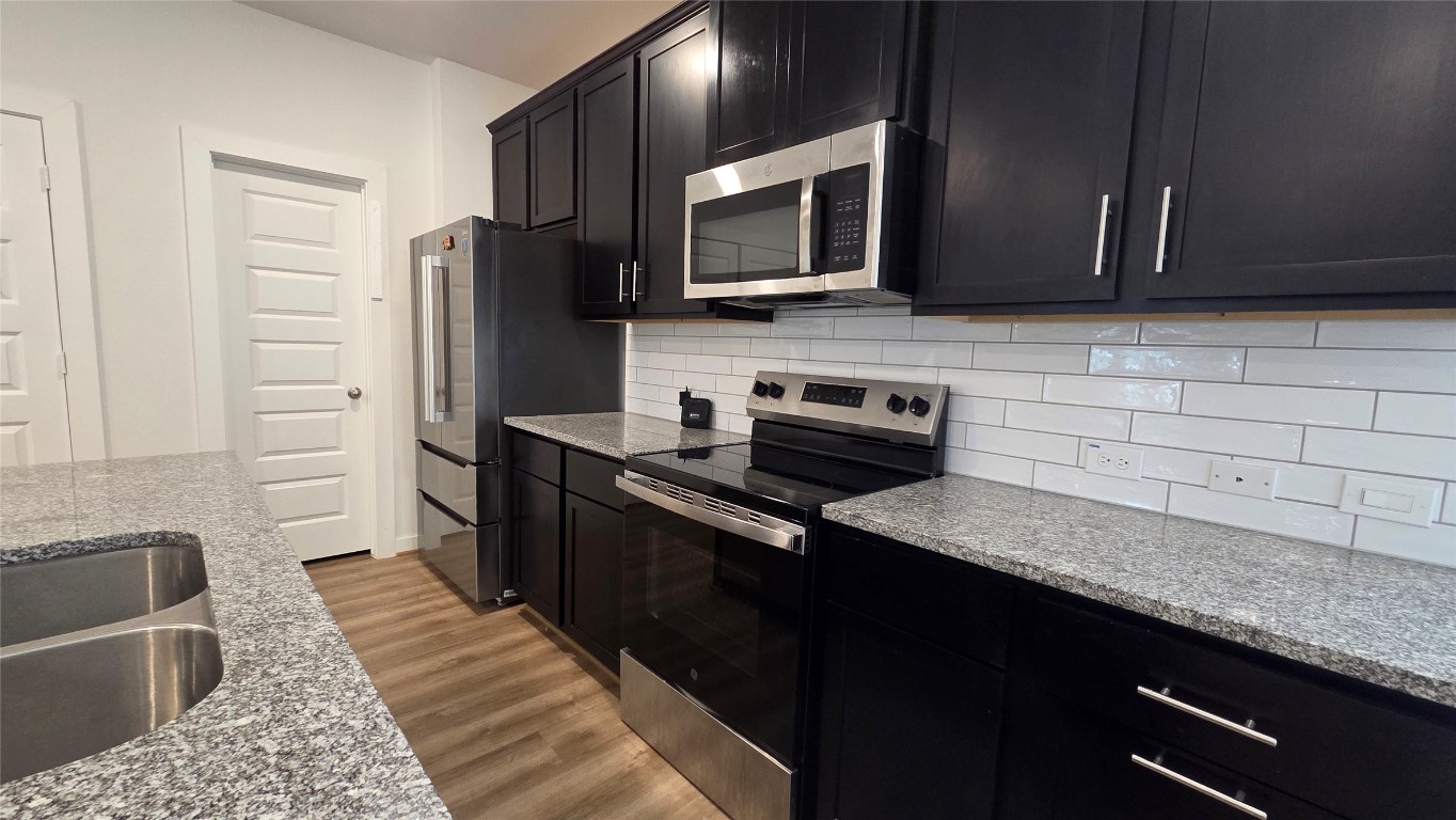 1015 Thor Roman Forest, TX 77357 - Photo 4 of 15 a kitchen with stainless steel appliances granite countertop a refrigerator microwave and sink