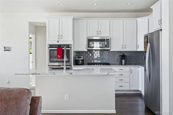 a large kitchen with kitchen island a living area and a flat screen tv