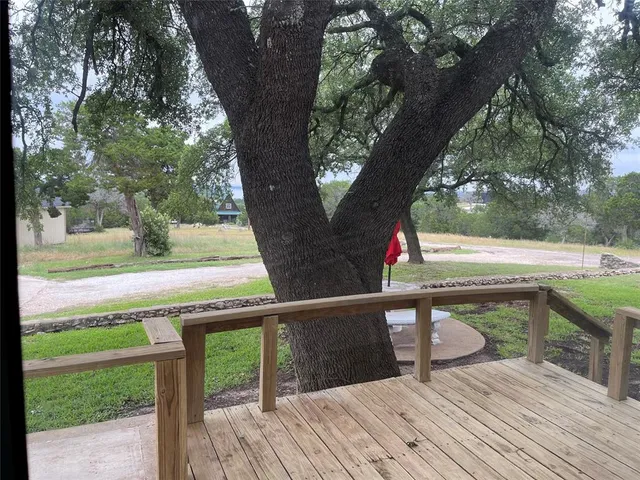a view of a wooden house with a big yard and large trees