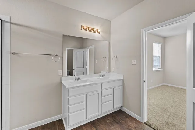 a spacious bathroom with a double vanity sink a mirror and a