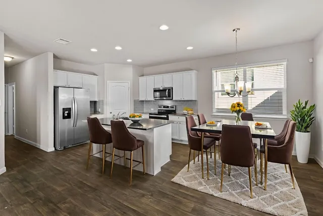 a kitchen with a dining table chairs refrigerator and microwave