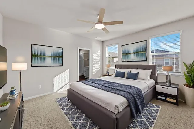 a bedroom with a large bed couch and two windows