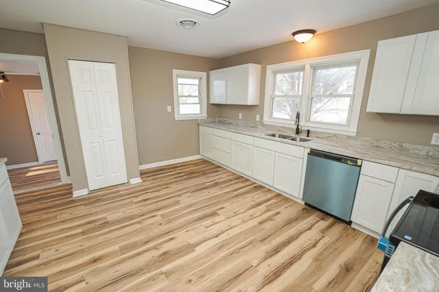 a kitchen with granite countertop a stove top oven a sink dishwasher and a refrigerator with wooden floor