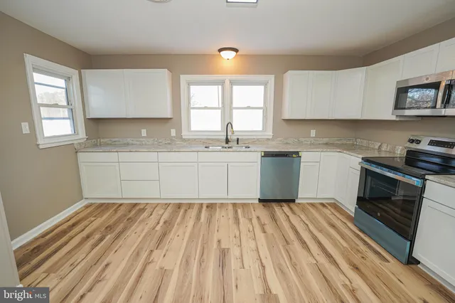 a kitchen with granite countertop a refrigerator stove top oven and sink