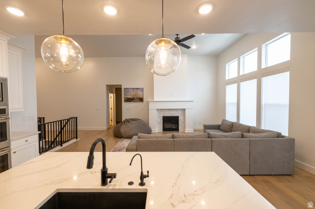 293 North Pheasant Drive Mapleton, UT 84664 - Photo 20 of 20 Kitchen featuring light wood-type flooring, open floor plan, white cabinets, light stone counters, and a high ceiling