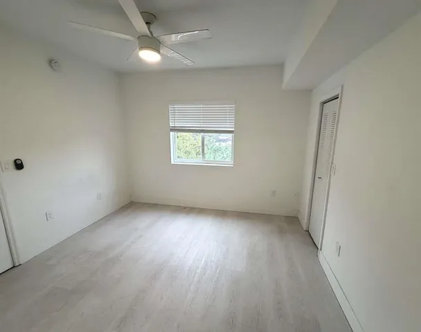 an empty room with a window and a ceiling fan