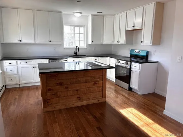 an empty room with wooden floor fireplace and windows