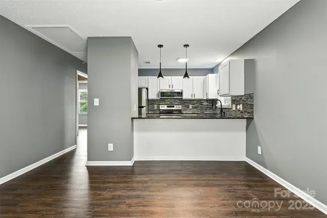 a view of kitchen with stainless steel appliances granite countertop white cabinets and wooden floor