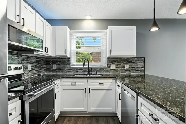 a kitchen with granite countertop a sink stainless steel appliances and cabinets