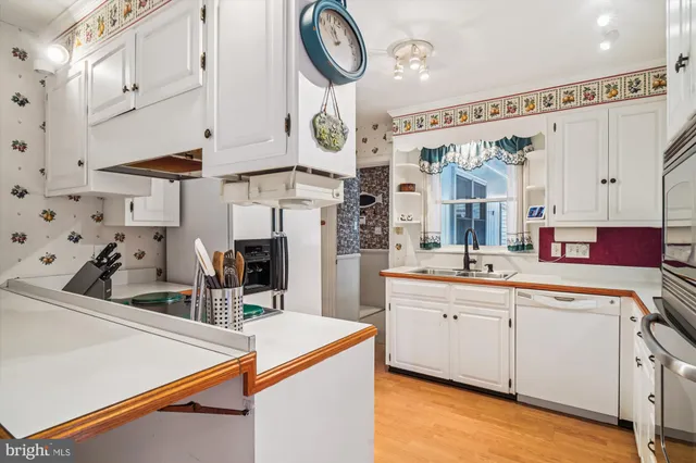 a kitchen with stainless steel appliances a sink a stove and white cabinets