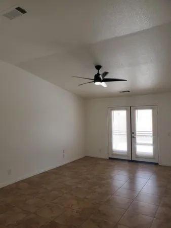 an empty room with windows and ceiling fan
