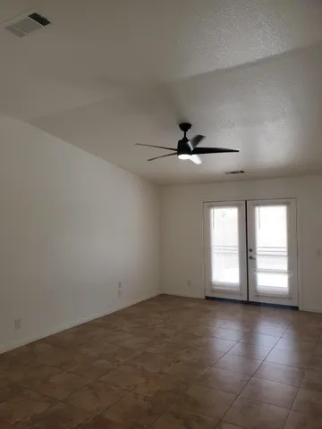 an empty room with windows and ceiling fan