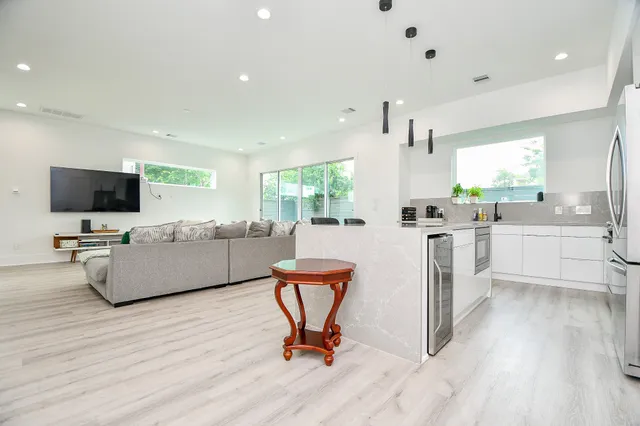 a view of a kitchen with kitchen island wooden floor and stainless steel appliances