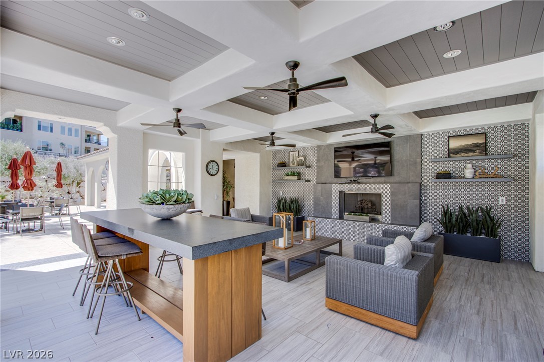 An expansive covered patio features a coffered ceiling and a modern outdoor fireplace.