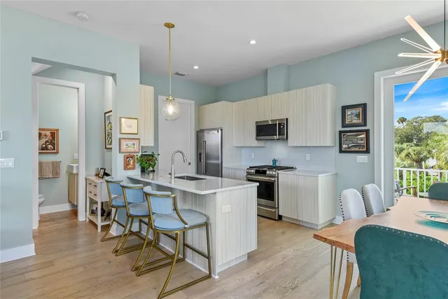 a kitchen with stainless steel appliances kitchen island granite countertop a refrigerator a stove top oven a sink dishwasher and white cabinets with wooden floor