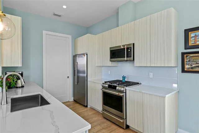 a kitchen with stainless steel appliances a stove a microwave and a hard wood floor