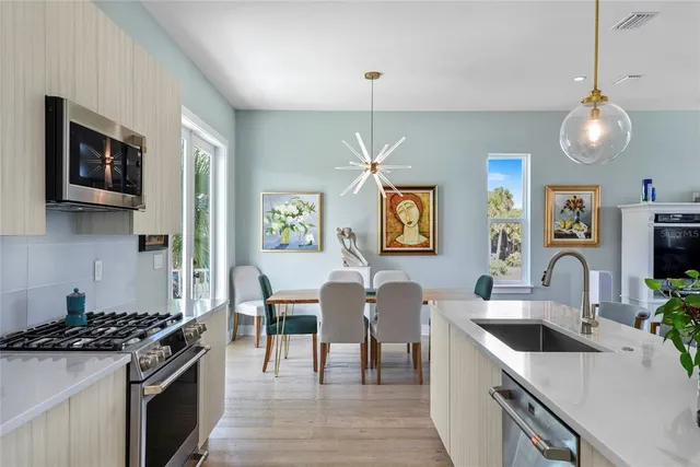a kitchen with stainless steel appliances a table and chairs in it