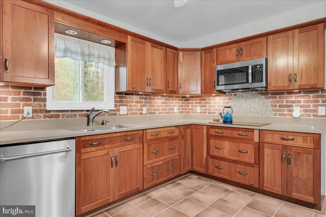 a kitchen with stainless steel appliances granite countertop wooden cabinets a sink and a window