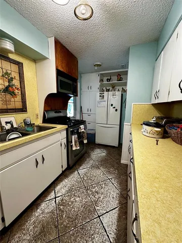 a kitchen with stainless steel appliances a stove a sink cabinets and a refrigerator