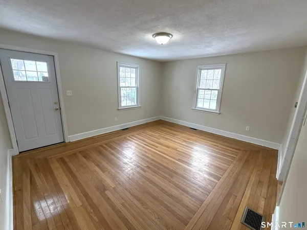 a view of empty room with window and wooden floor