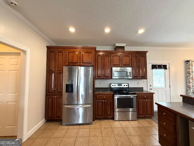 a kitchen with stainless steel appliances granite countertop a stove top oven a refrigerator and a sink