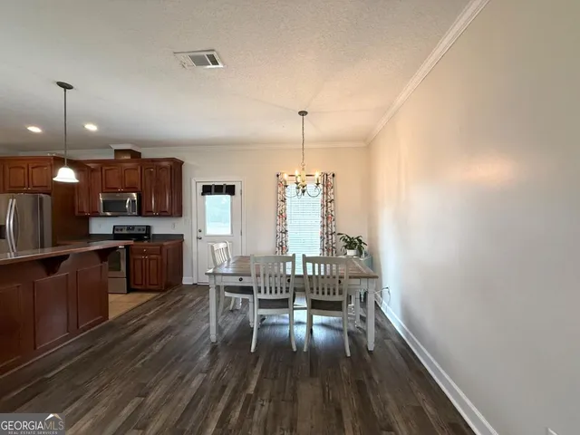a kitchen with stainless steel appliances a kitchen island hardwood floor sink stove dining table and chairs