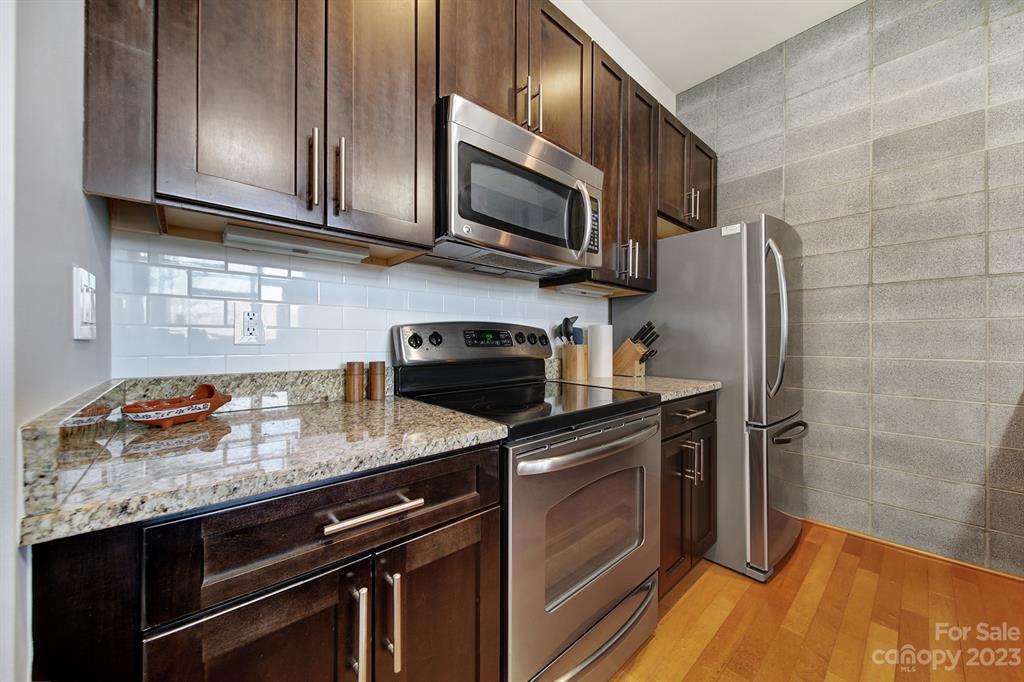 2116 McClintock Road, Unit 122 Charlotte, NC 28205 - Photo 4 of 27 a kitchen with stainless steel appliances granite countertop a stove microwave refrigerator and sink